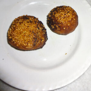 Bihari Anarsa rice-flour and sesame sweet — two golden sesame-crusted discs on a plate