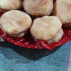 Plate of golden Anarsa rice-flour sweets dusted with sesame, served in a festive bowl