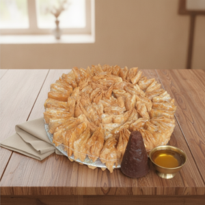 Gur Desi Ghee Khaja — iconic tower with jaggery cone and brass ghee bowl, premium festival grade, on warm wood with linen