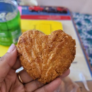 Close-up of a heart-shaped Thekua showing its crisp golden crust and dense jaggery-sweetened wheat texture