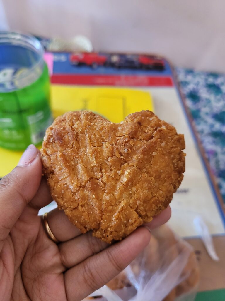 Close-up of a heart-shaped Thekua showing its crisp golden crust and dense jaggery-sweetened wheat texture