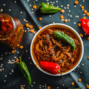 Bihari bharwa lal mirch ka achar, stuffed red chilli pickle in mustard oil in a white bowl